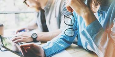 Photo d'une personne qui regarde une tablette en tenant ses lunettes